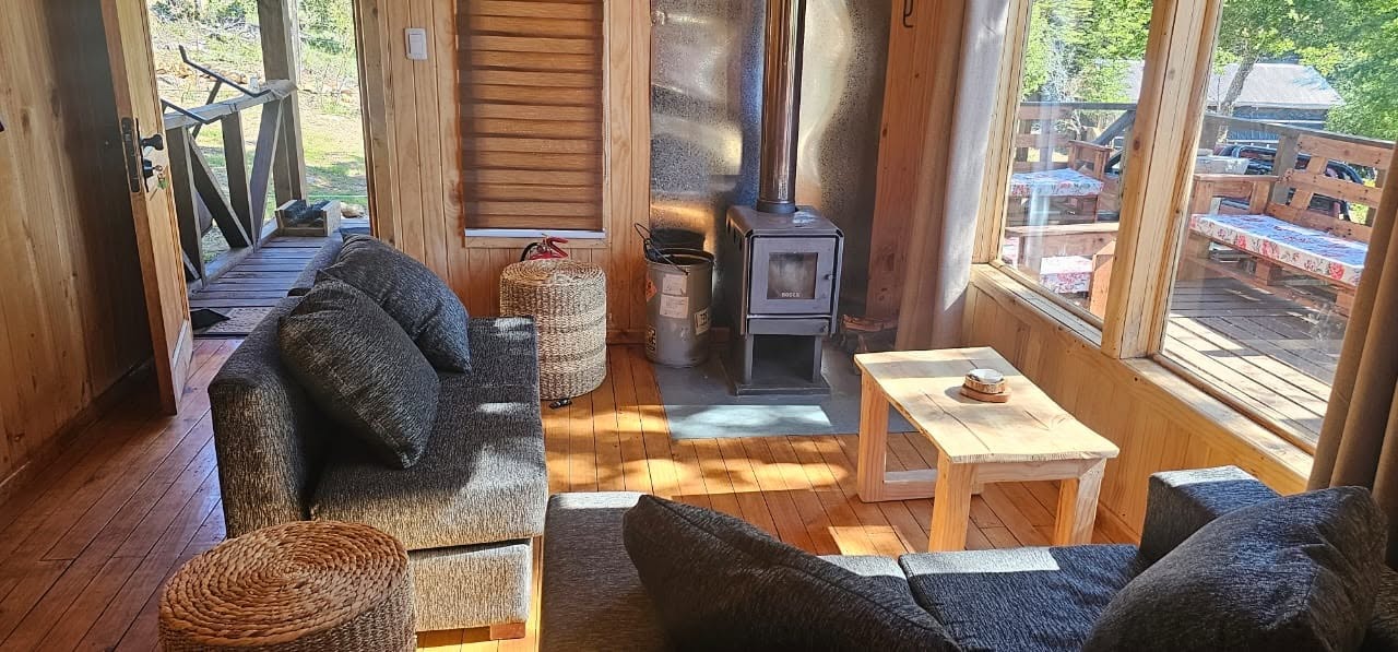 Living con sillones grises y estufa a leña