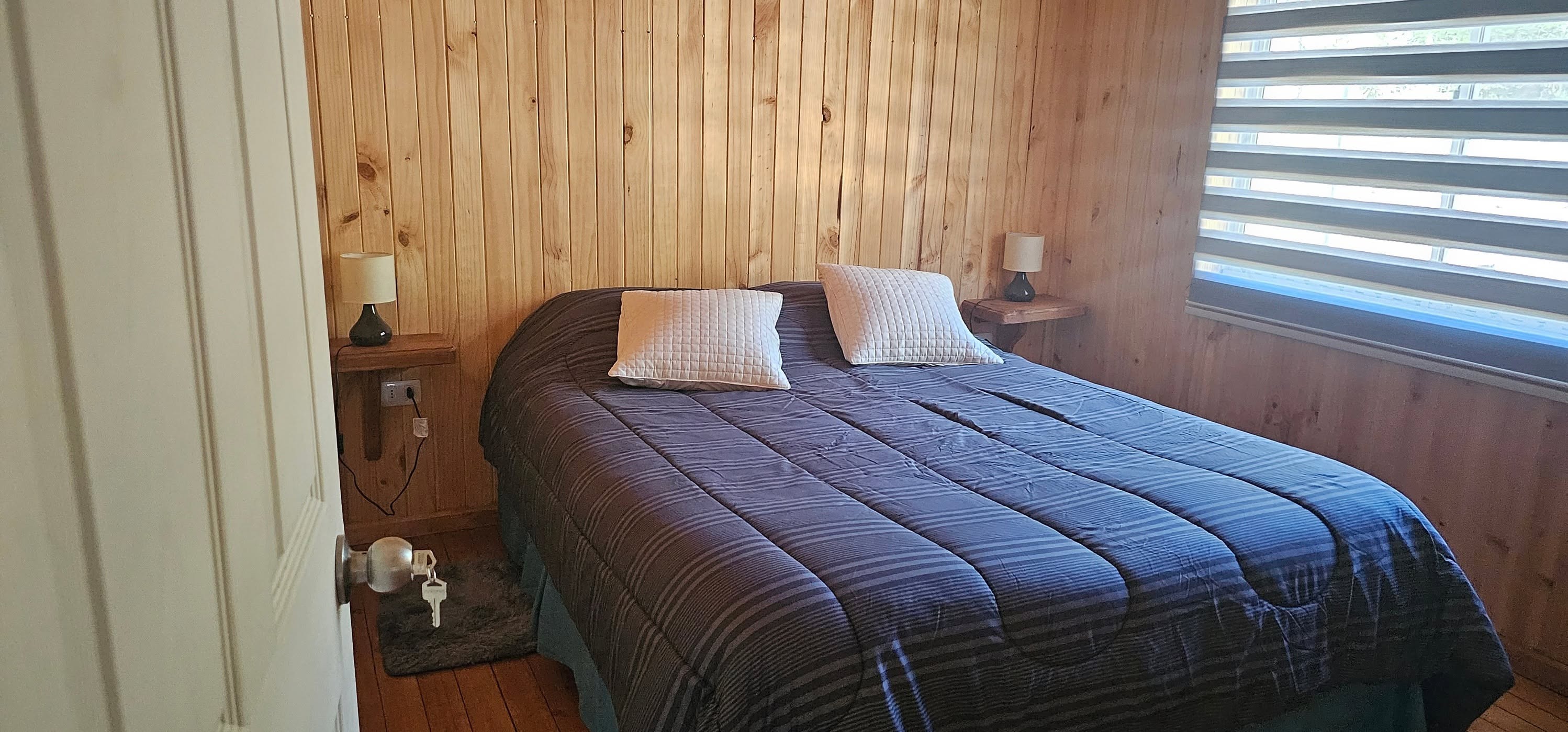 Dormitorio matrimonial con muros de madera y cama de dos plazas